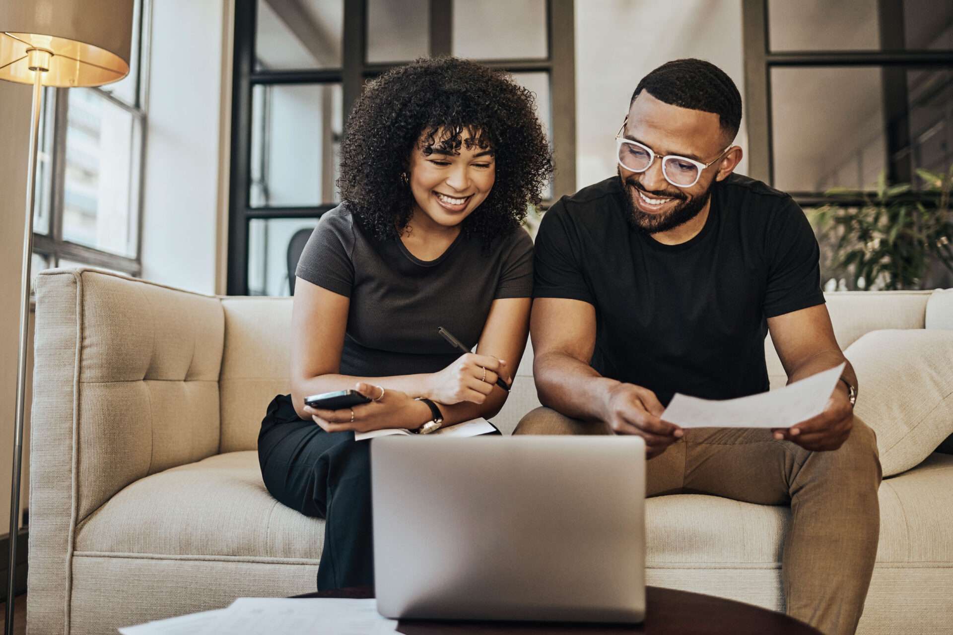 Woman and man in glasses on couch in front of laptop