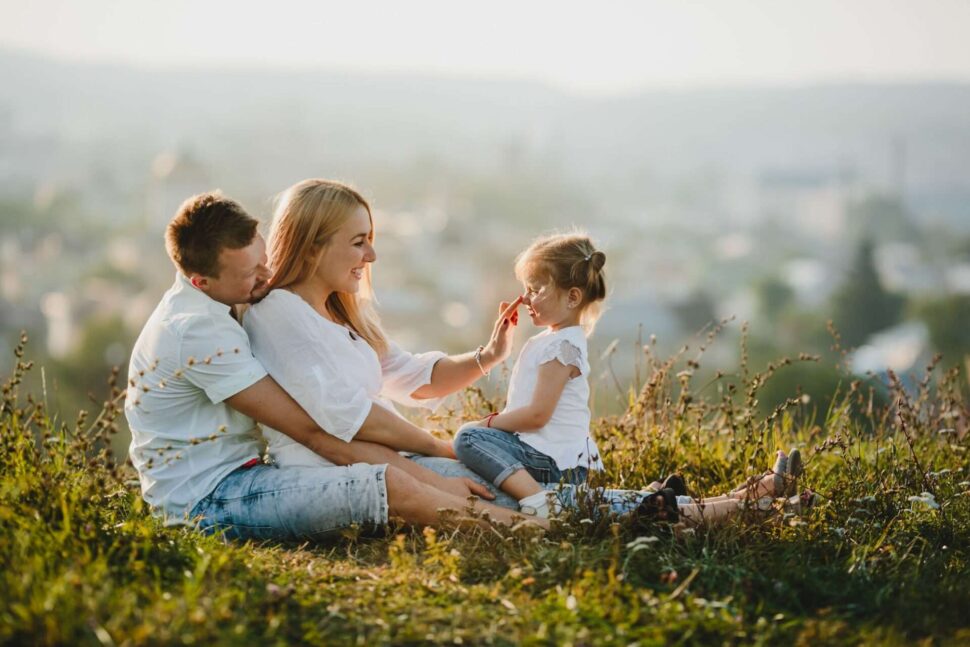 parents sitting on grass with child