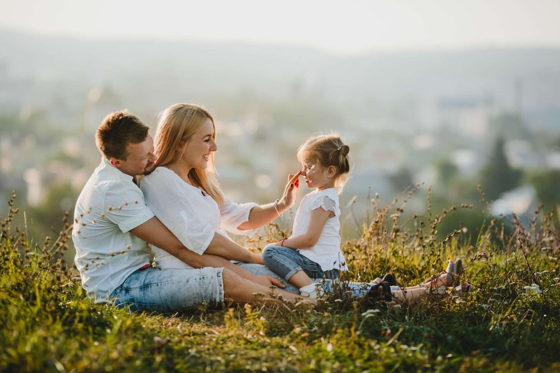 parents sitting on grass with child