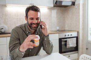 Man holding pill bottle while on the phone
