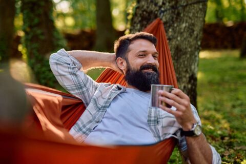 Insights Man relaxing in hammock with coffee